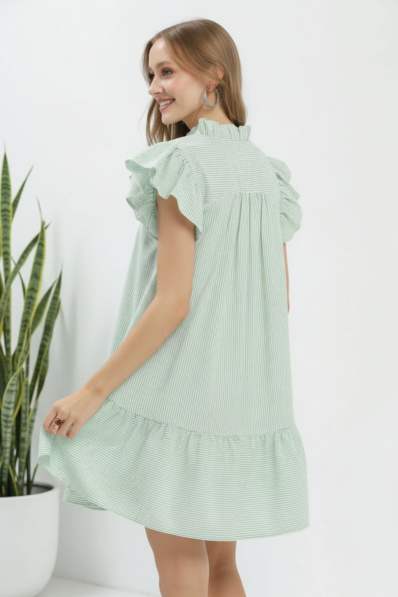 Woman wearing a light green dress with ruffled sleeves on a white background