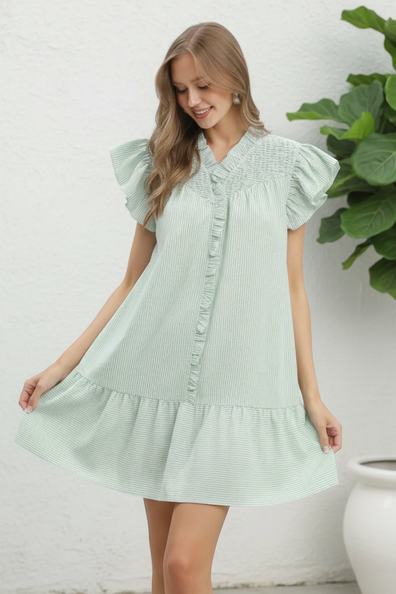 Woman wearing a light green dress with ruffled sleeves on a white background