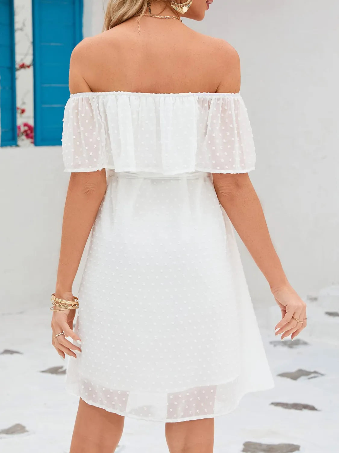 Woman wearing a white off-shoulder dress with a blurred background