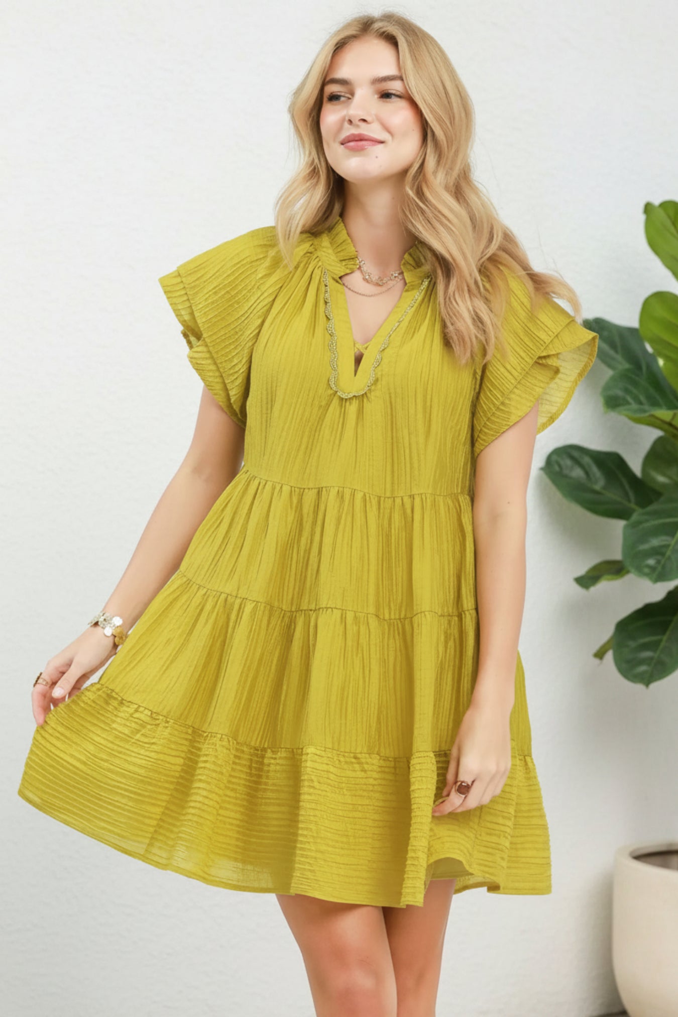 Woman wearing a yellow dress with ruffled sleeves on a white background