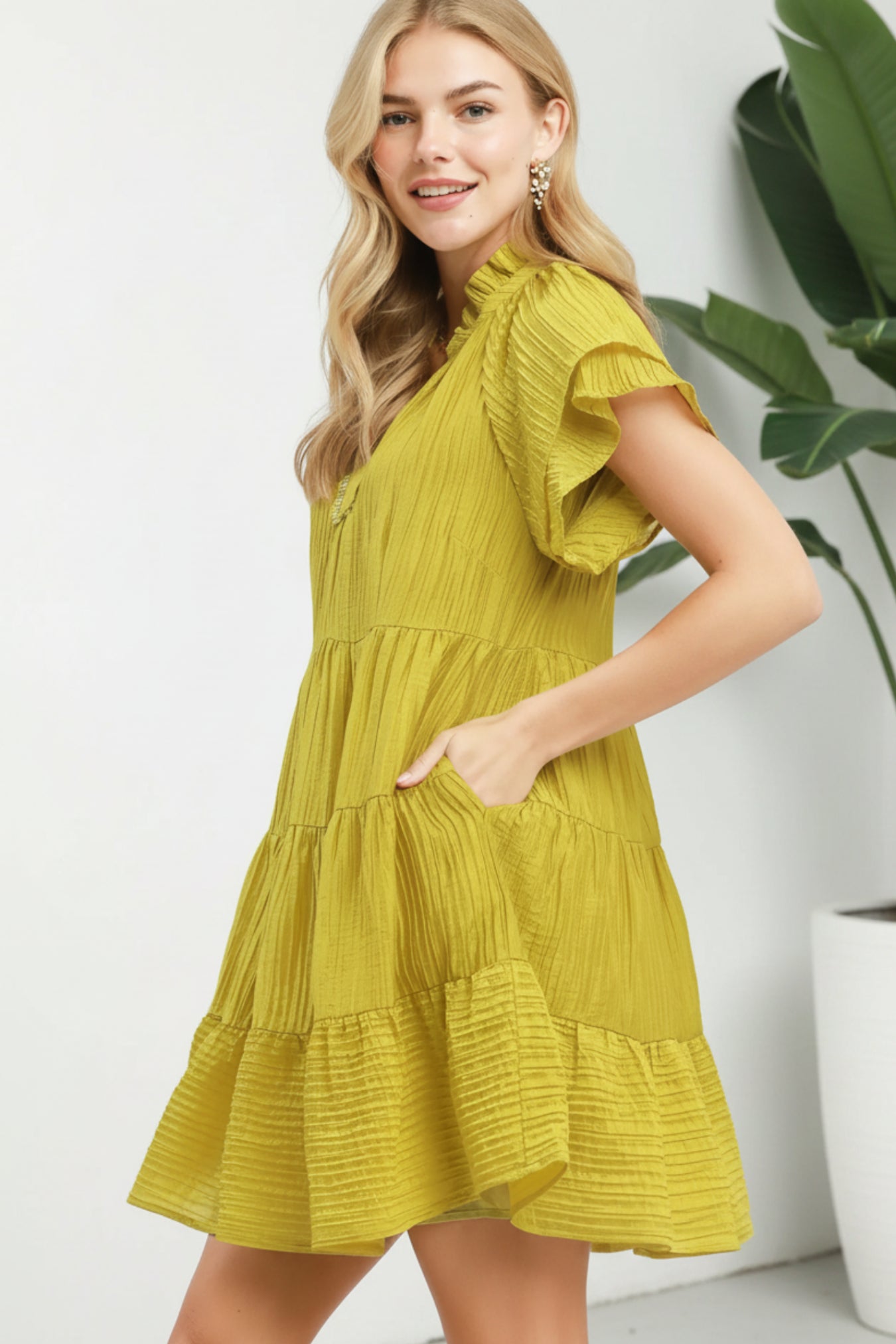 Woman wearing a yellow dress with ruffled sleeves on a white background