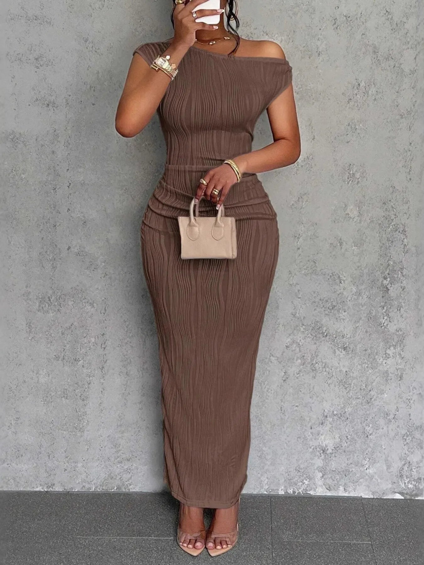 Woman wearing a brown ribbed dress against a gray wall