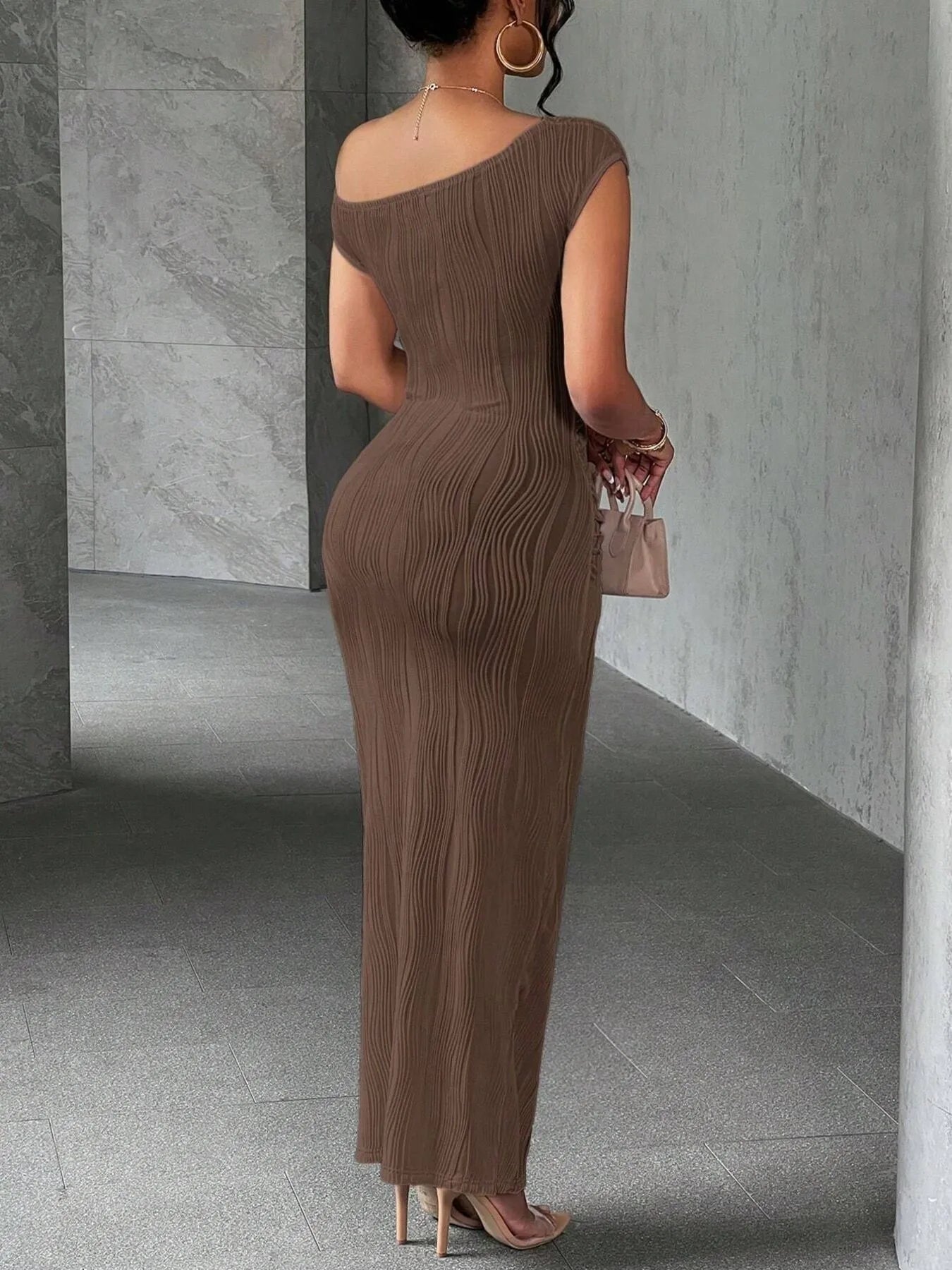 Woman wearing a brown one-shoulder dress in a minimalistic setting