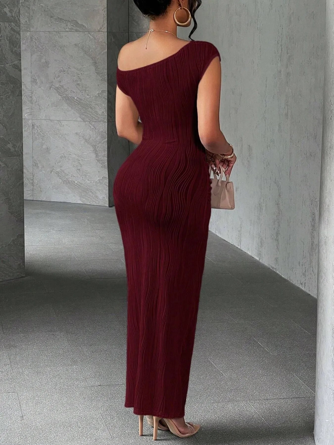 Woman wearing a burgundy one-shoulder dress in an indoor setting.