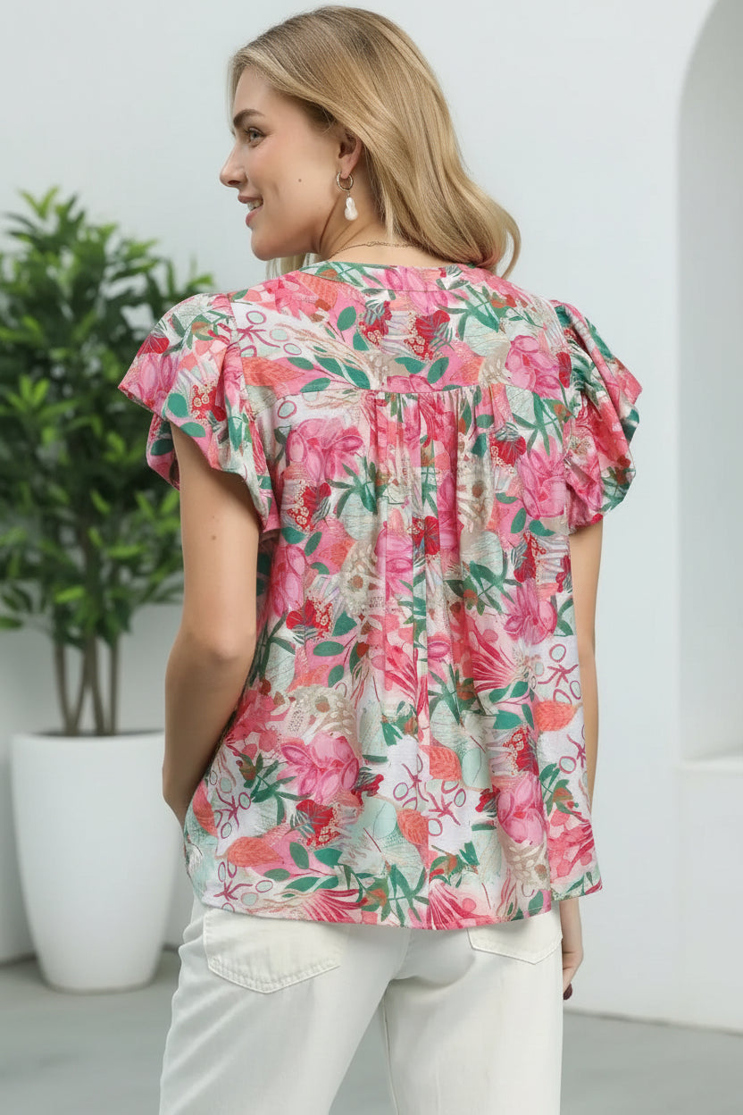 Woman wearing a floral blouse with ruffled sleeves in an indoor setting.