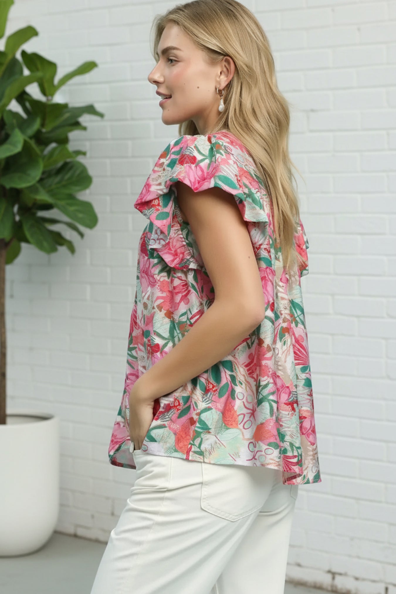 Woman wearing a floral blouse with a white brick wall background
