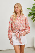 Woman wearing a floral blouse with a tie waist on a pink background
