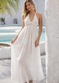 Woman in a white dress standing by a pool with columns in the background