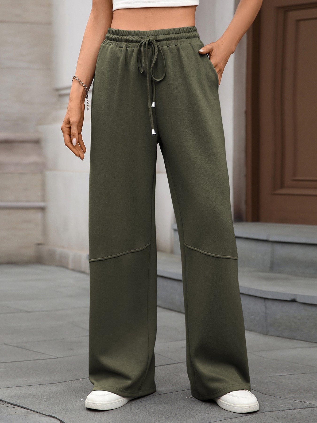 Person wearing olive green wide-leg pants with a neutral background