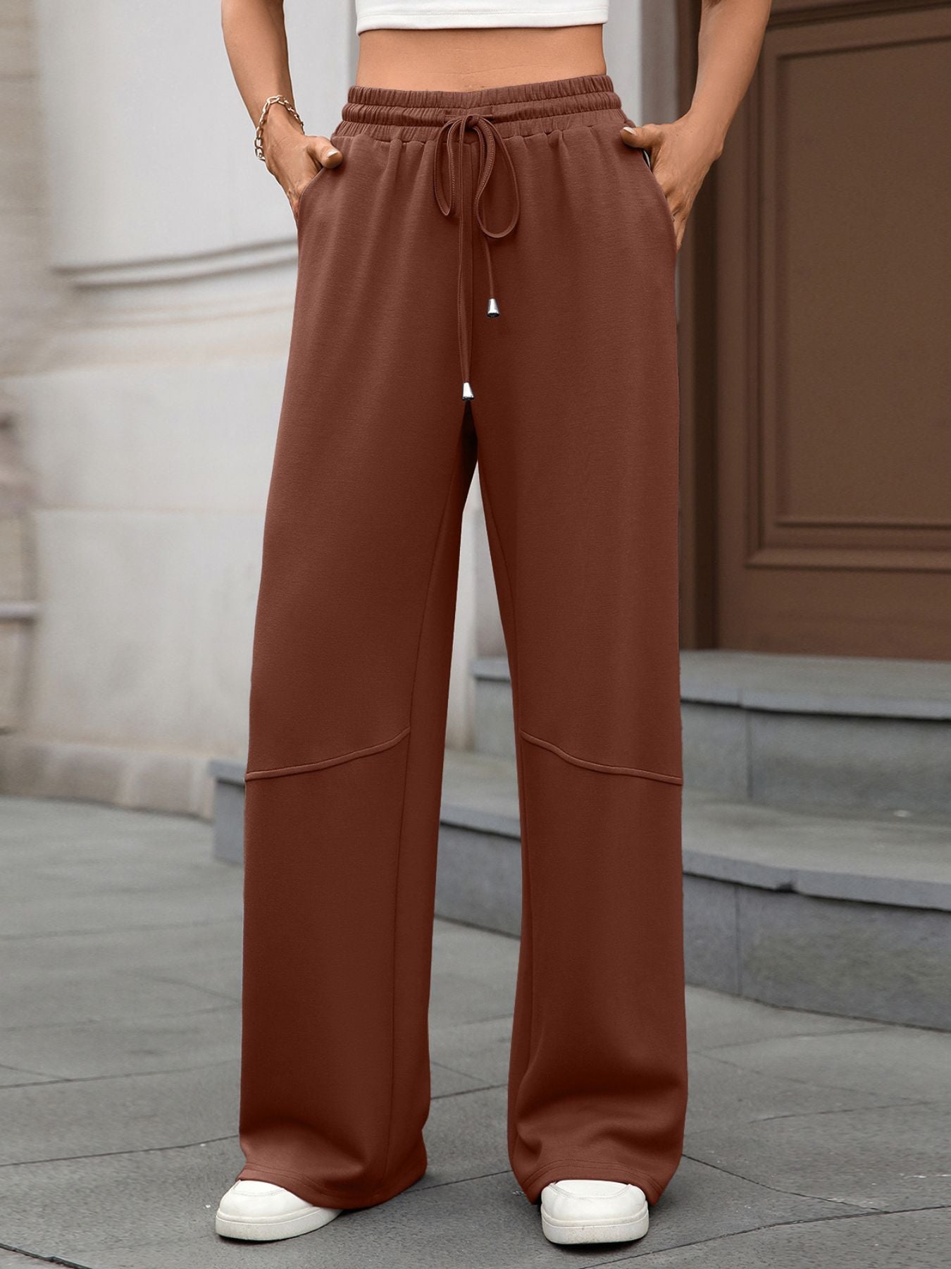 Person wearing brown wide-leg pants with a blurred background