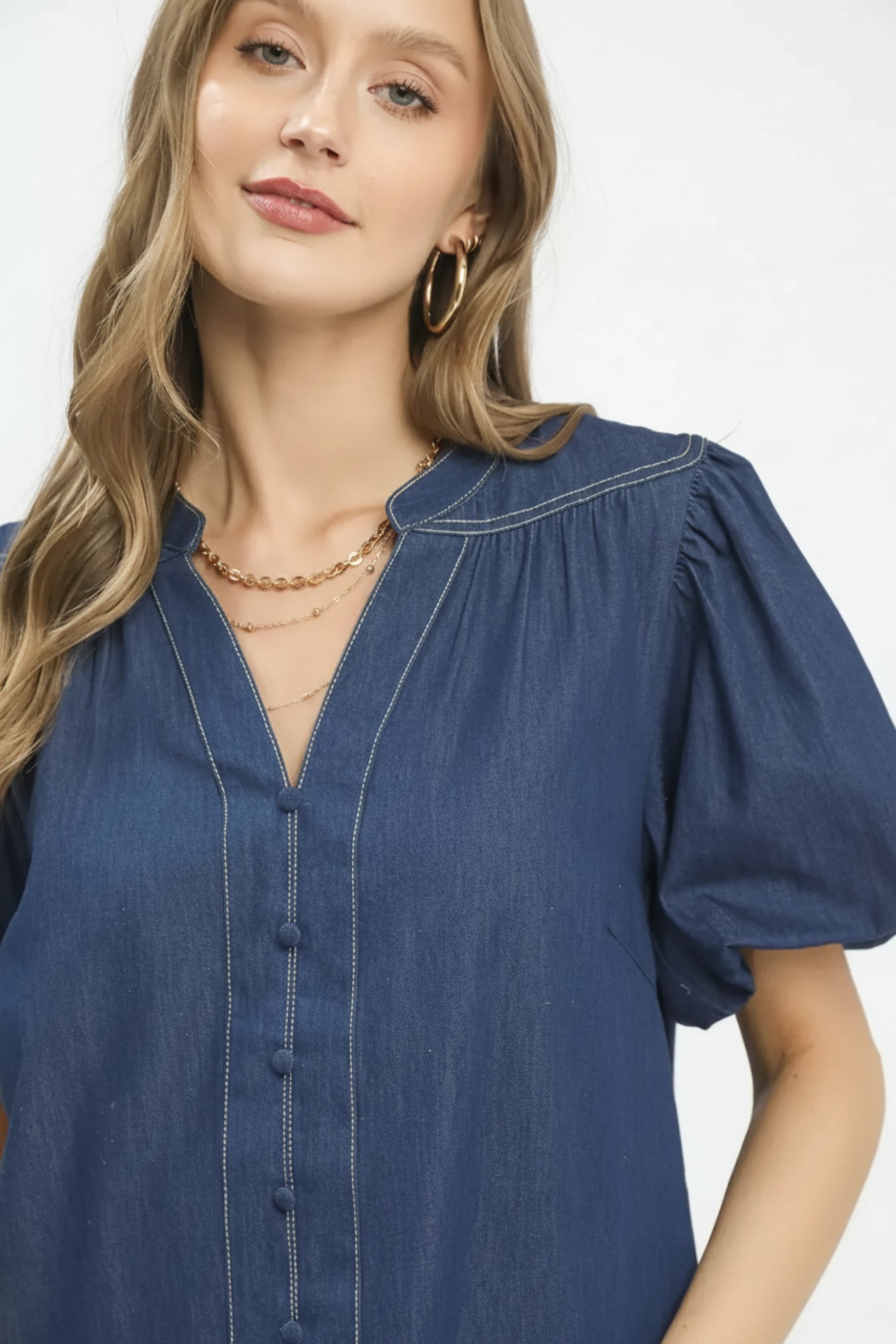 Woman wearing a blue denim dress with puff sleeves on a white background