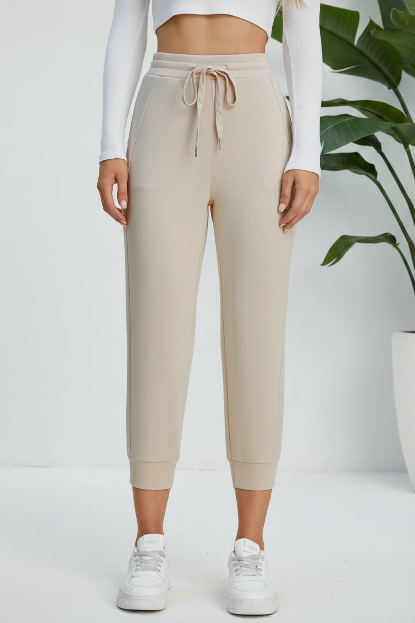Beige jogger pants worn by a person on a beige background