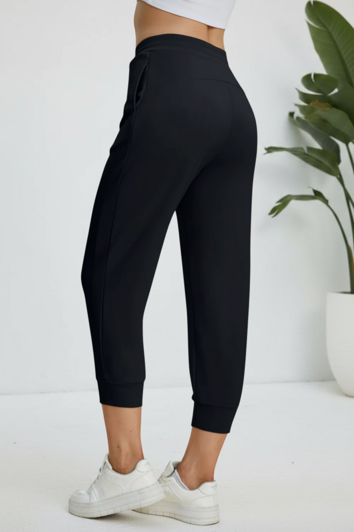 Black jogger pants worn by a person on a beige background