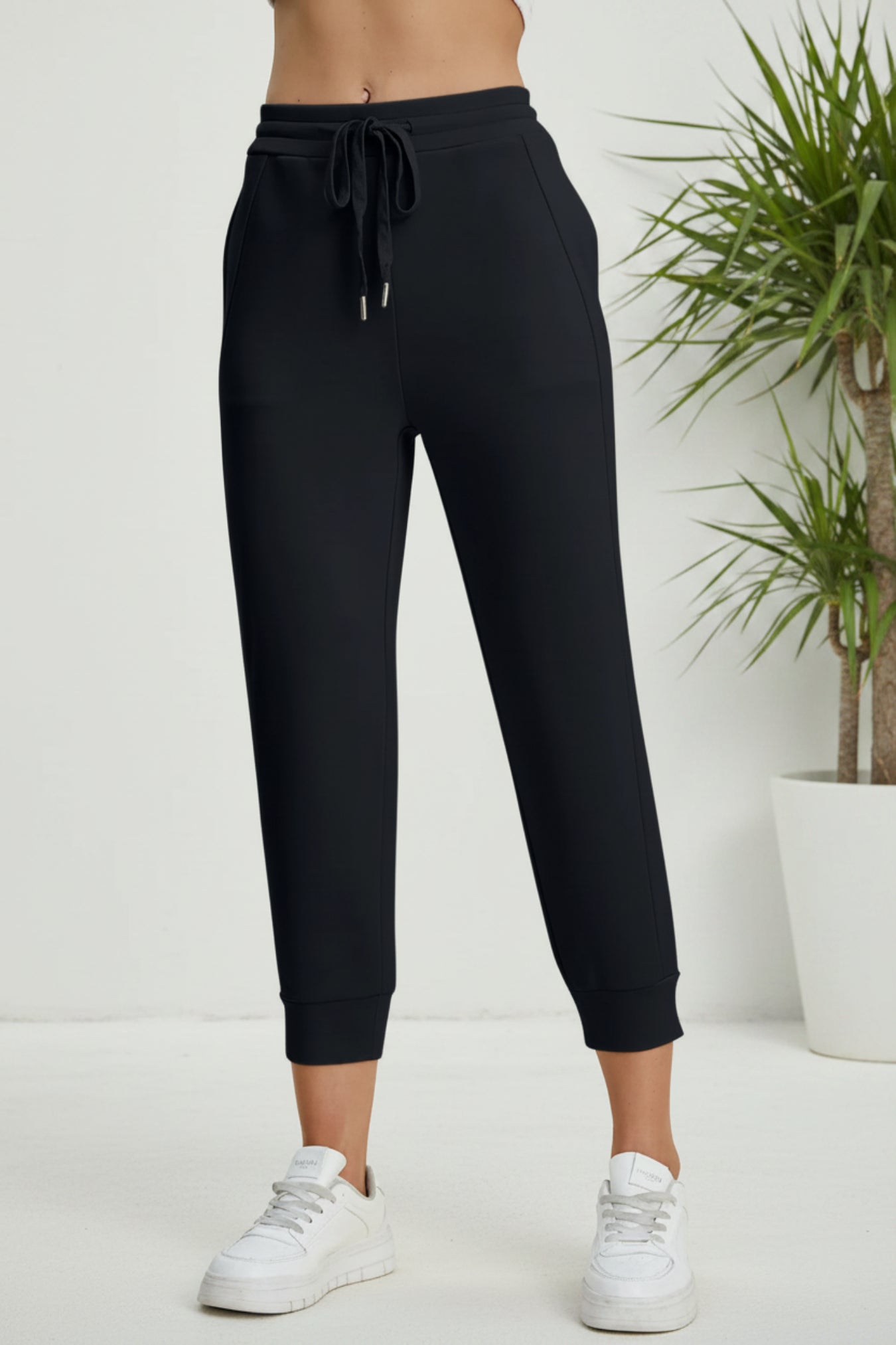 Black jogger pants worn by a person on a beige background