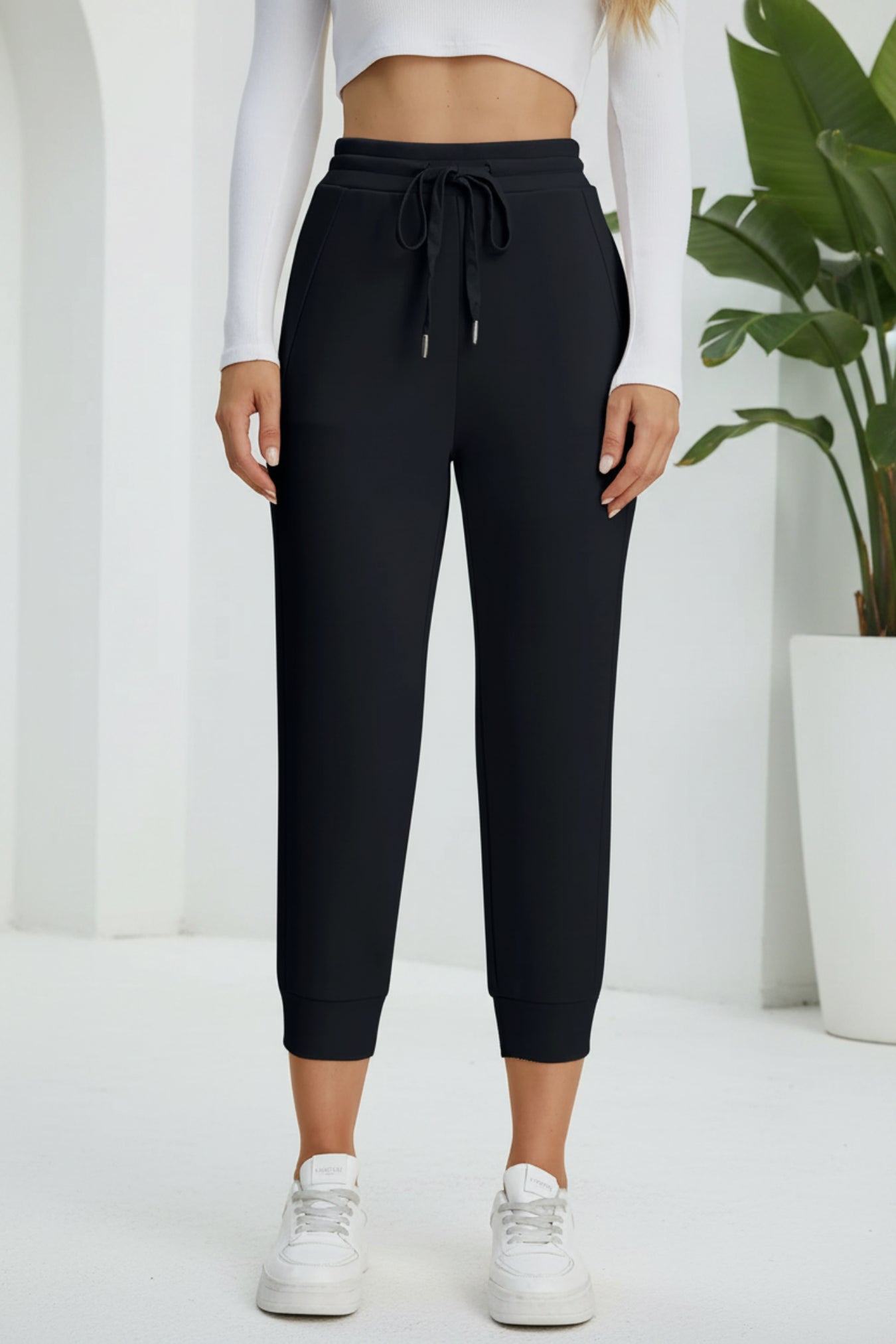 Person wearing black jogger pants with a beige background