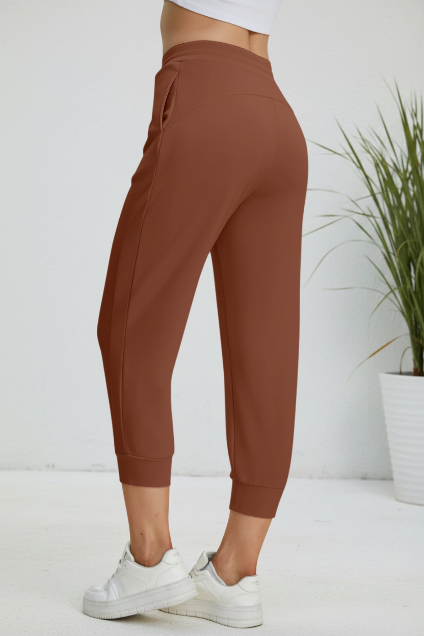 Brown jogger pants worn by a person on a beige background