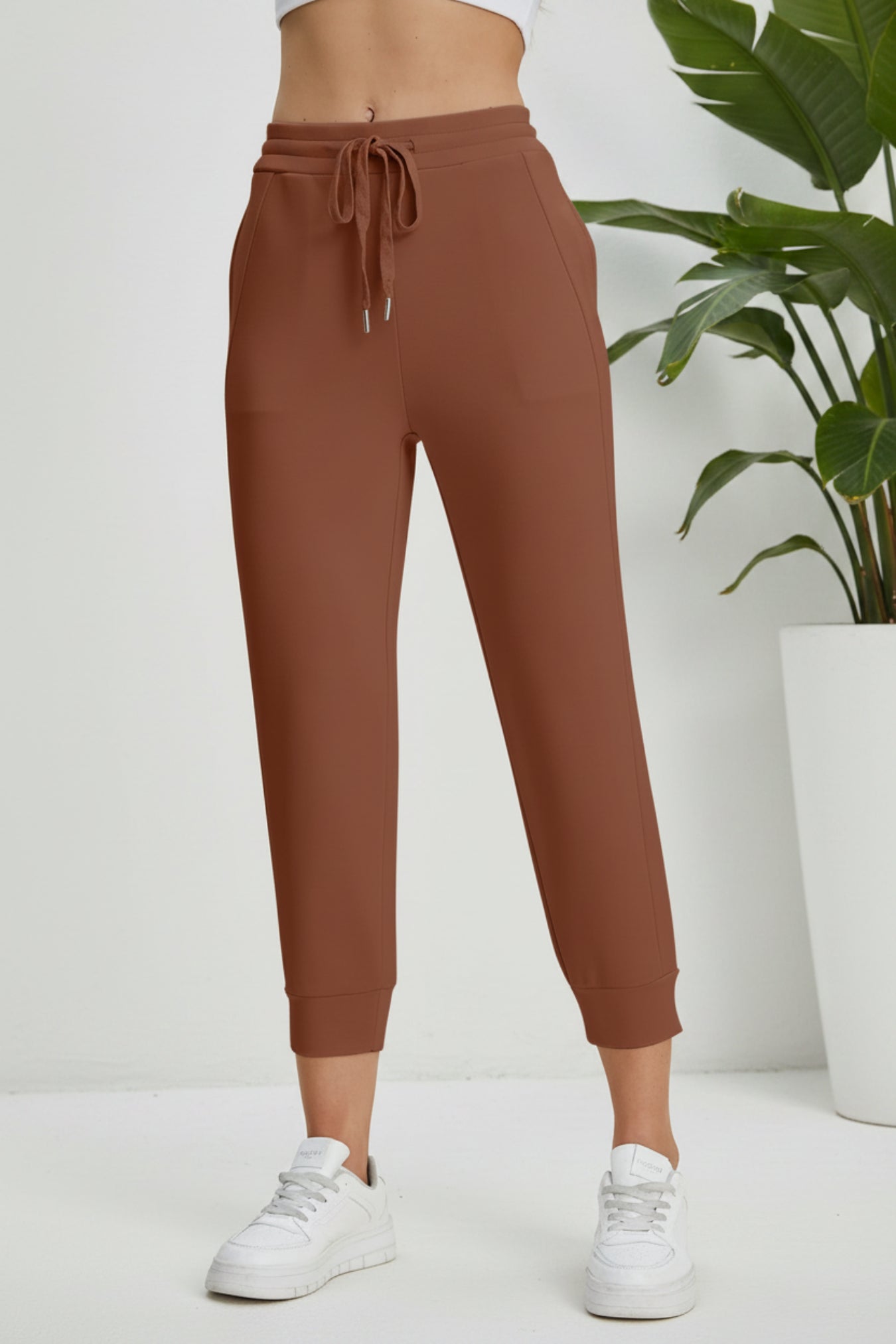 Brown sweatpants worn by a person on a beige background