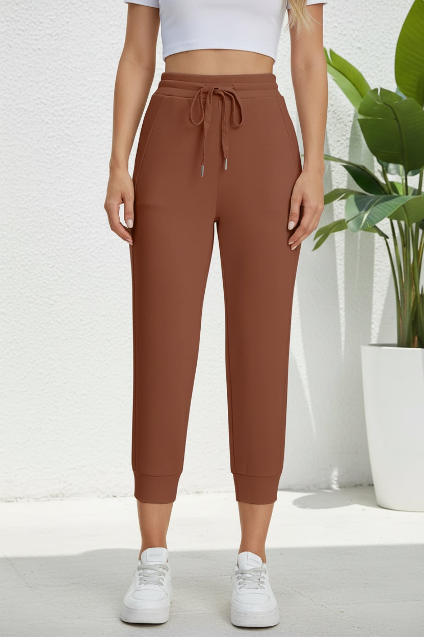 Brown jogger pants worn by a person on a beige background