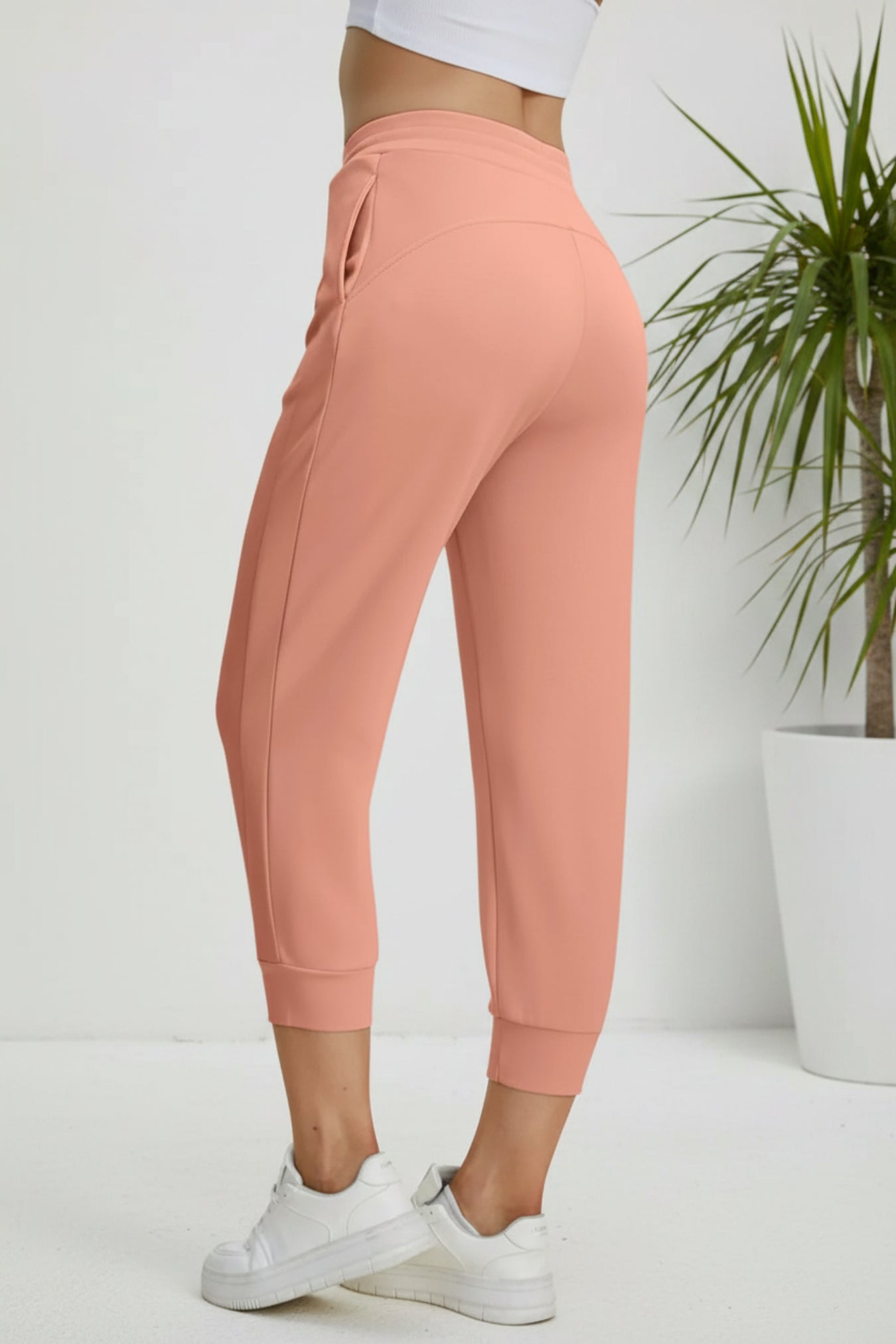 Coral jogger pants worn by a person on a beige background
