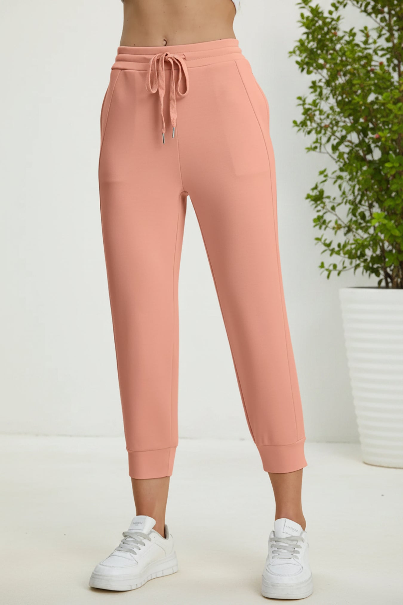 Peach-colored sweatpants worn by a person on a beige background