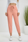 Person wearing pink sweatpants and white sneakers on a beige background