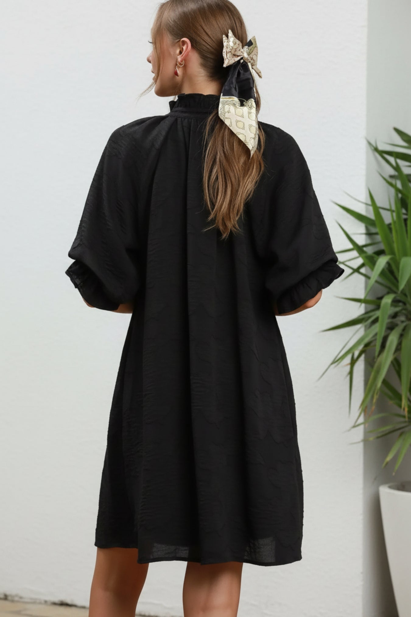Person wearing a black dress against a white background