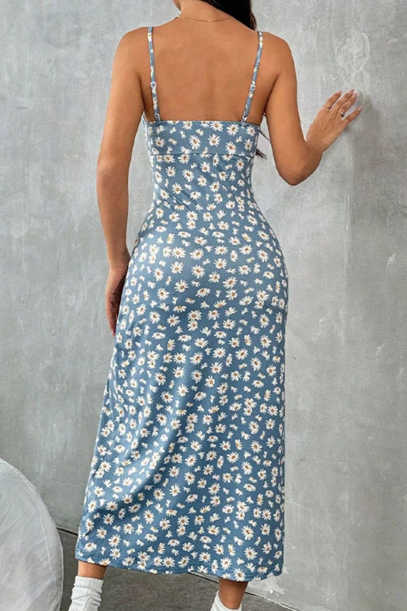 Woman wearing a blue floral dress against a gray wall