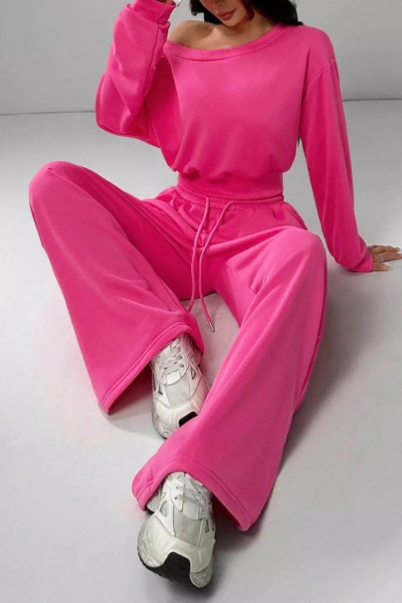 Person wearing a bright pink tracksuit sitting on a light gray floor.