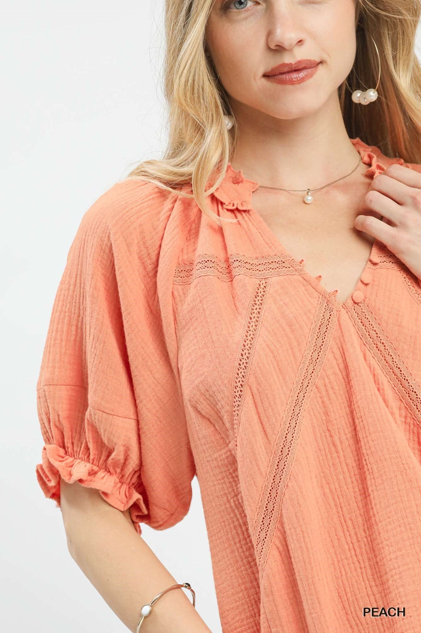 Woman wearing a peach-colored blouse with a plain background