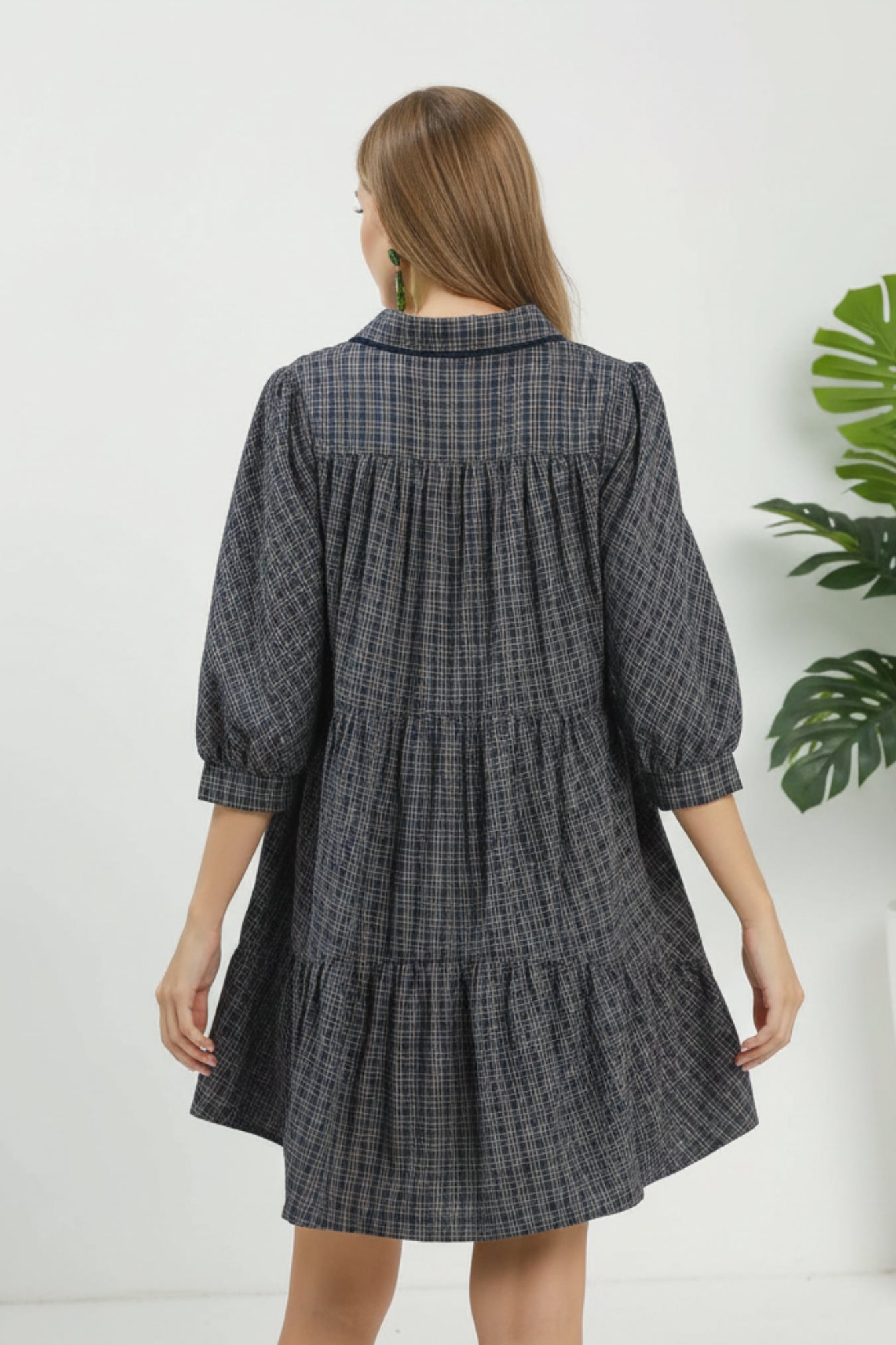Woman wearing a navy plaid dress with a plain background