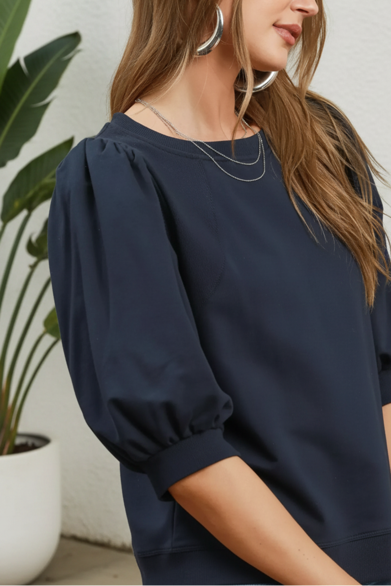 Woman wearing a navy blue blouse with puffed sleeves against a white background