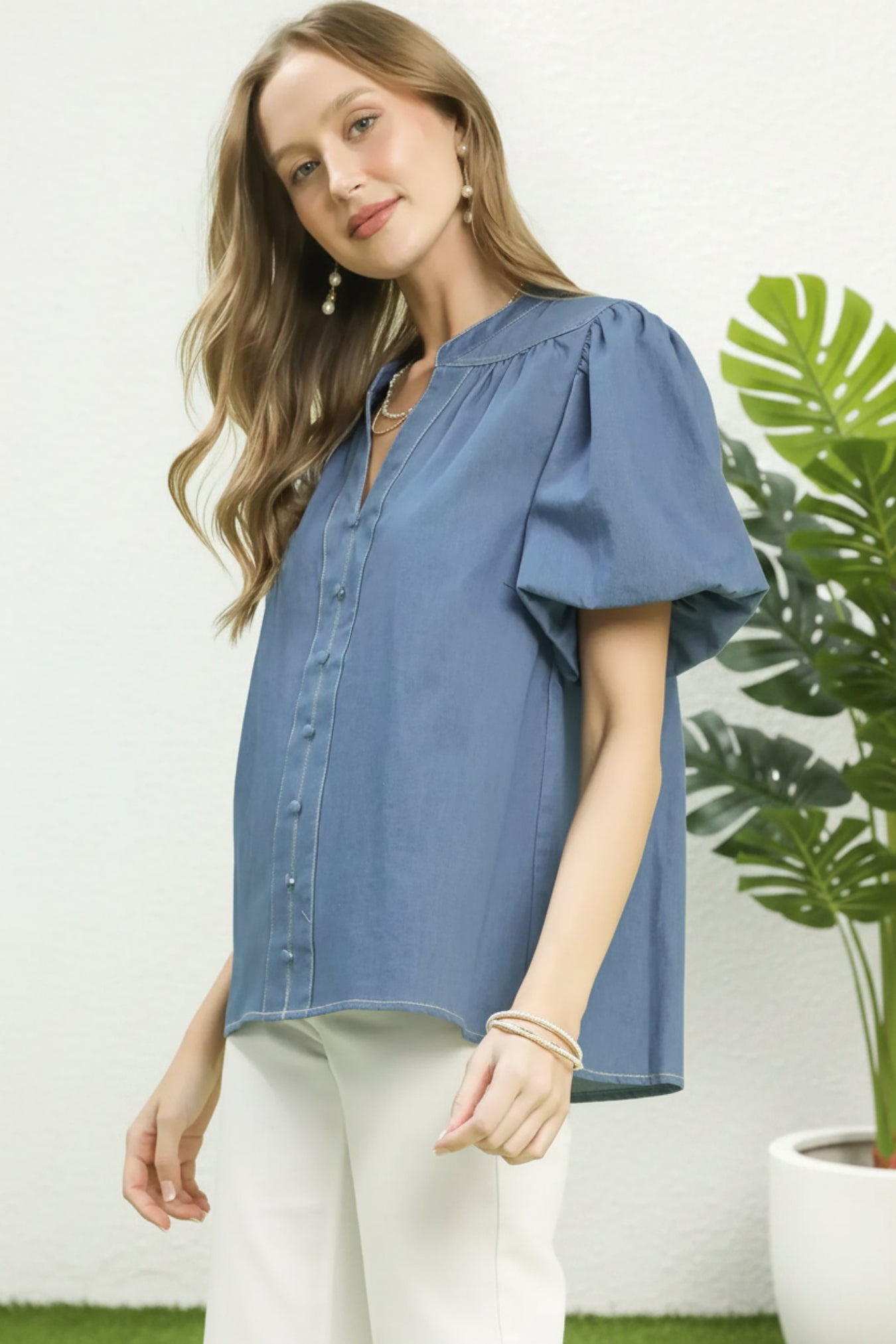 Woman wearing a light denim blouse with puff sleeves on a white background