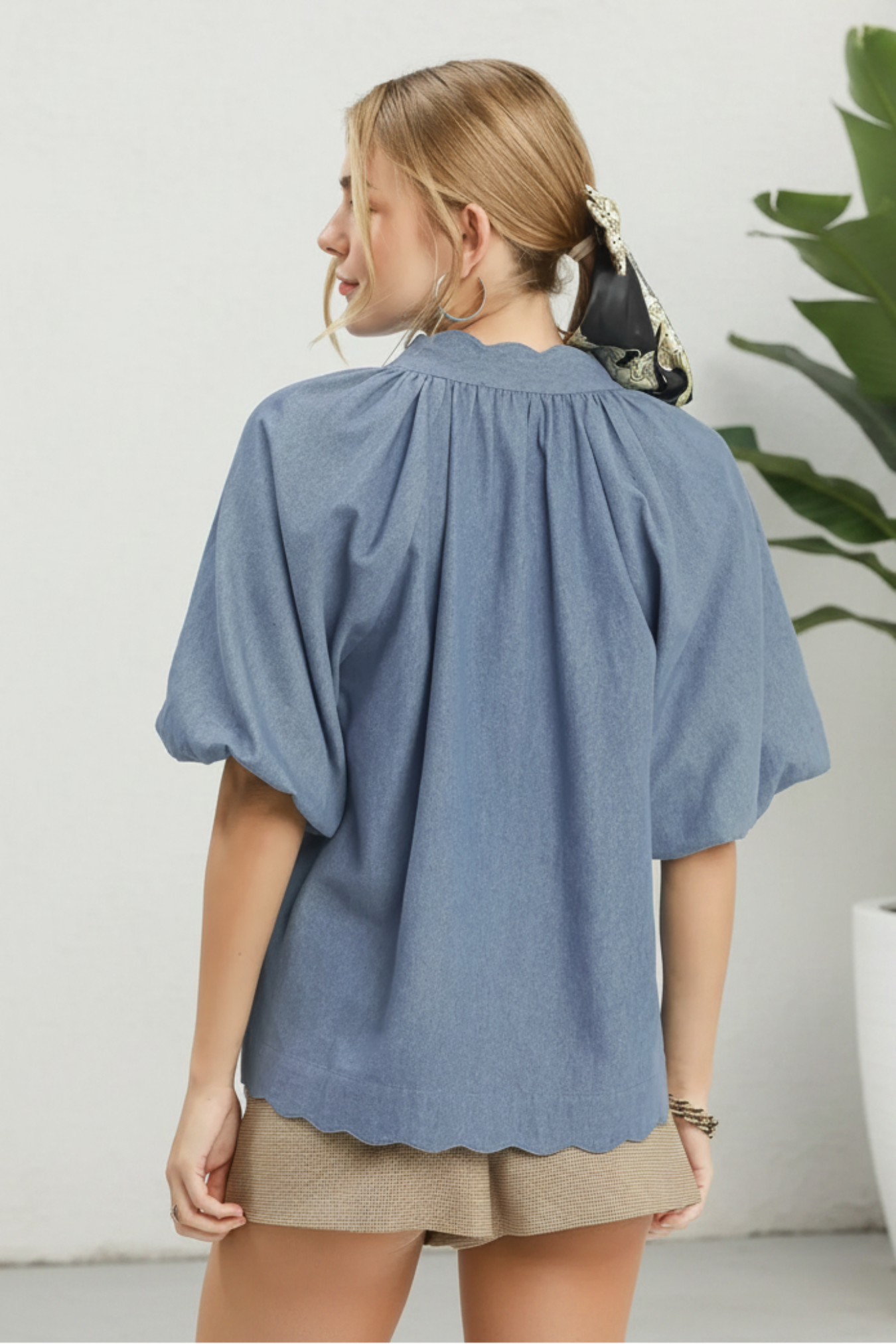 Woman wearing a blue denim blouse with a plain background