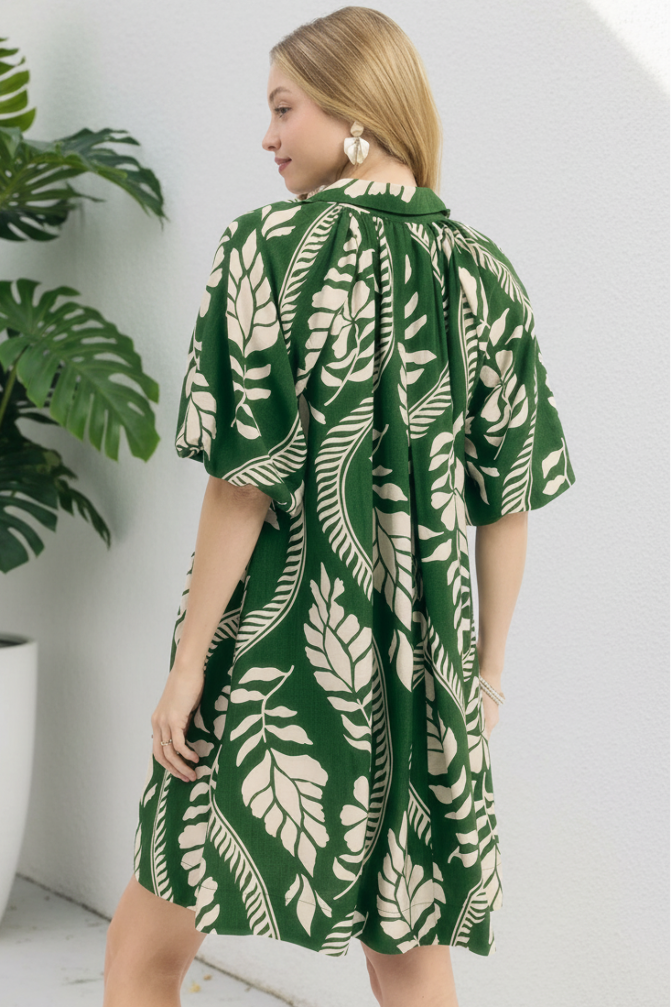 Woman wearing a green and cream leaf-patterned dress on a white background