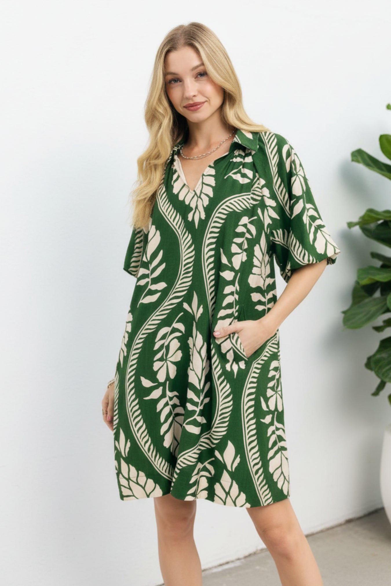 Woman wearing a green and cream leaf-patterned dress on a white background