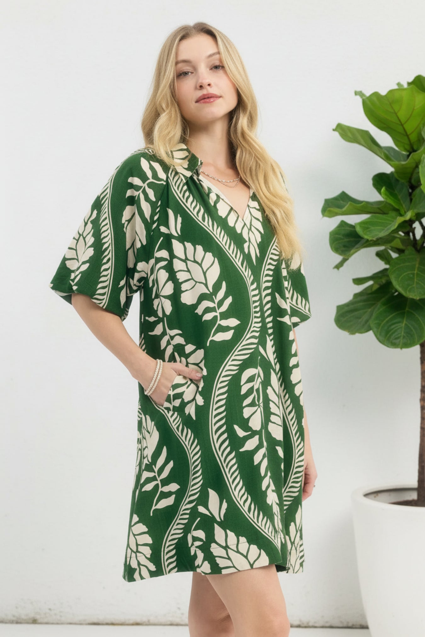 Woman wearing a green and cream leaf-patterned dress on a white background