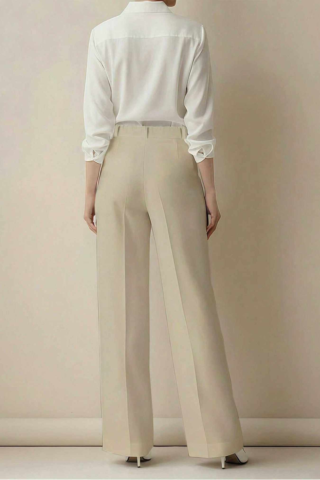 Person wearing a white shirt and beige pants against a plain background