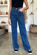 Person wearing blue jeans standing indoors with a neutral background