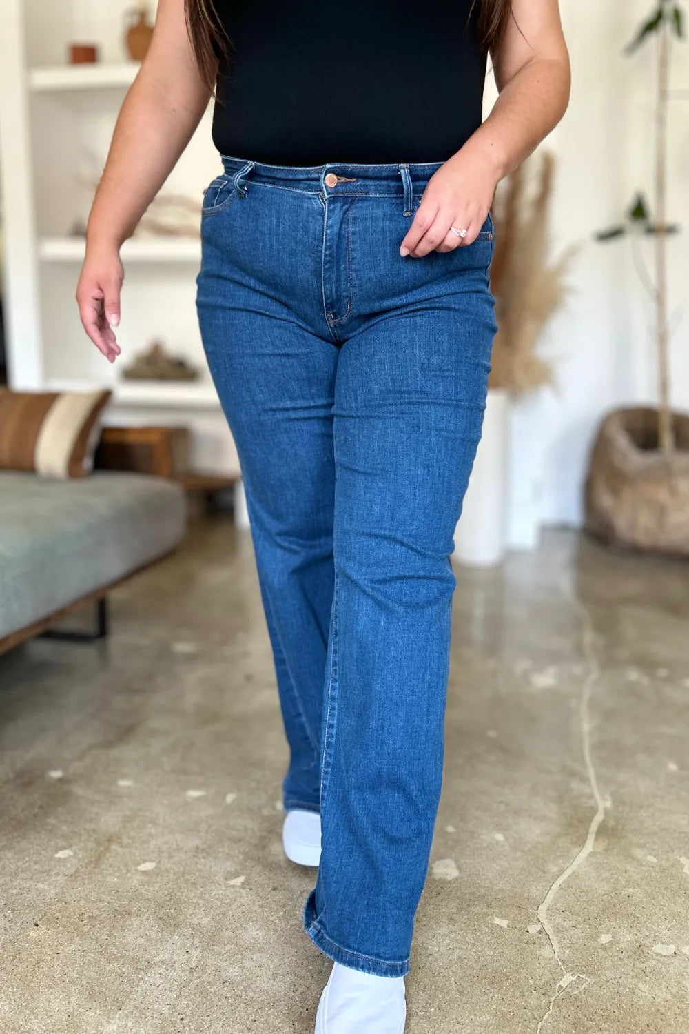 Person wearing blue jeans and a black top in an indoor setting