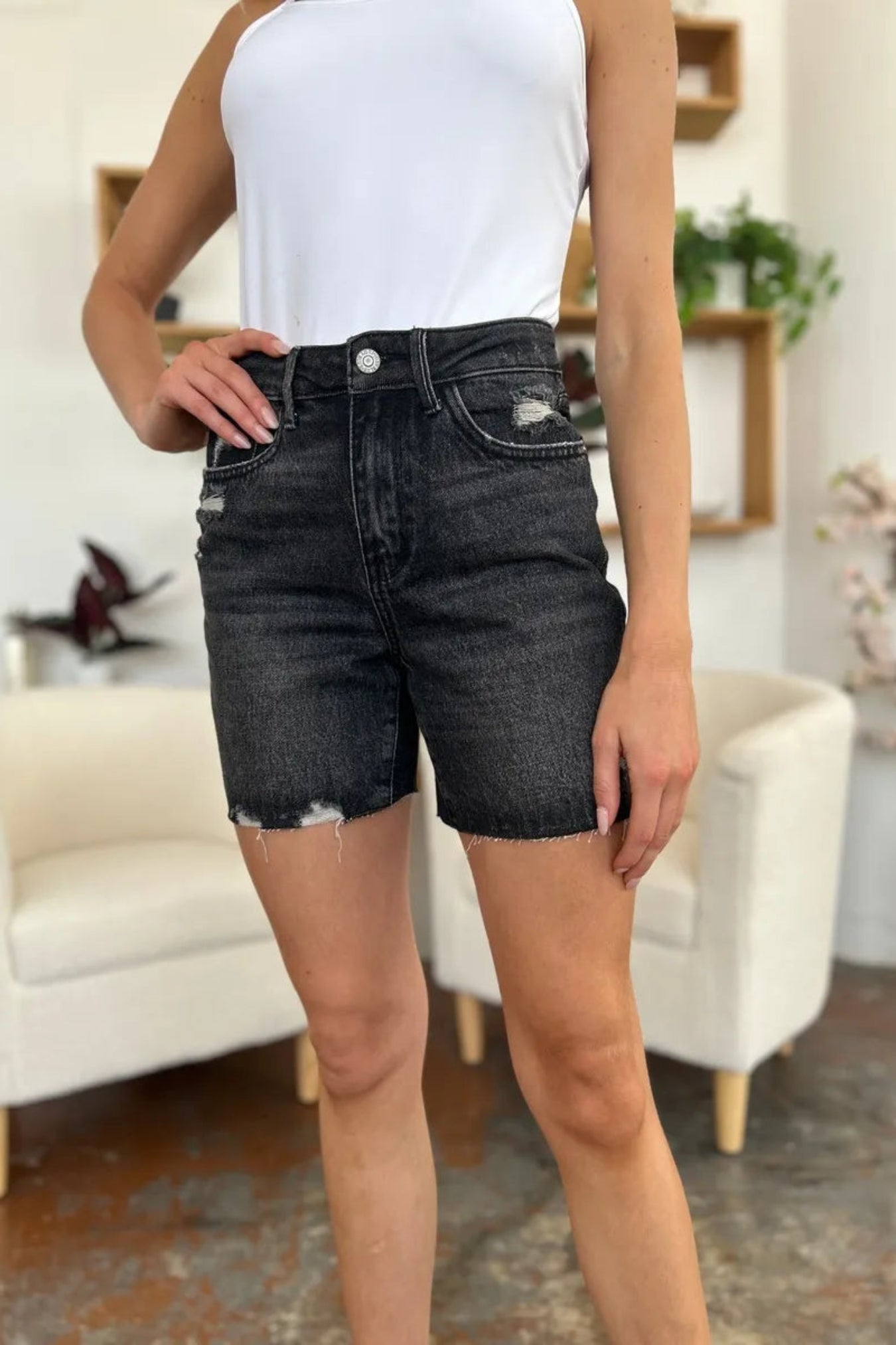Person wearing black denim shorts in a room with a white couch and decorative items.