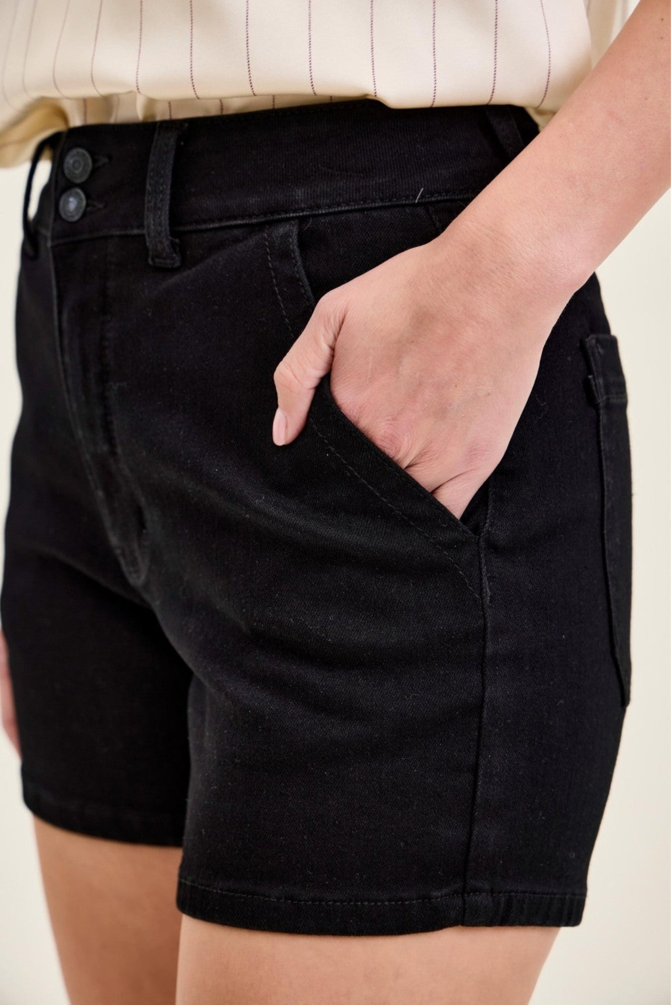 Person wearing black shorts with a neutral background