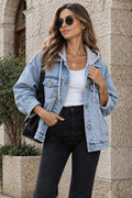A woman walking on a cobblestone street wearing a light-wash blue denim jacket over a white top, black flare jeans, and white sneakers, with a black shoulder bag.