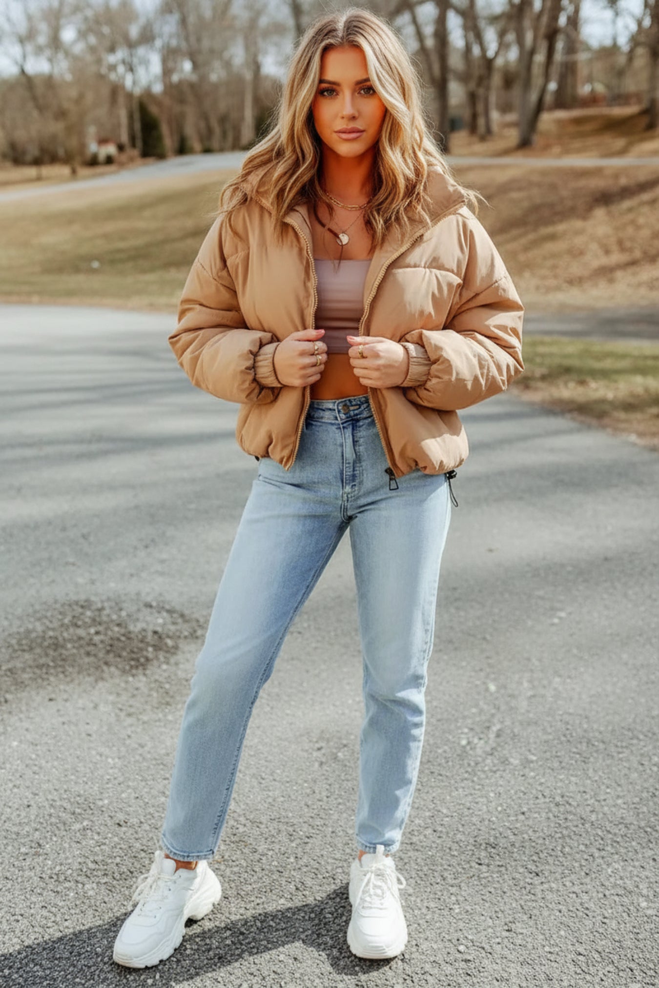 Person wearing a beige puffer jacket and light blue jeans outdoors