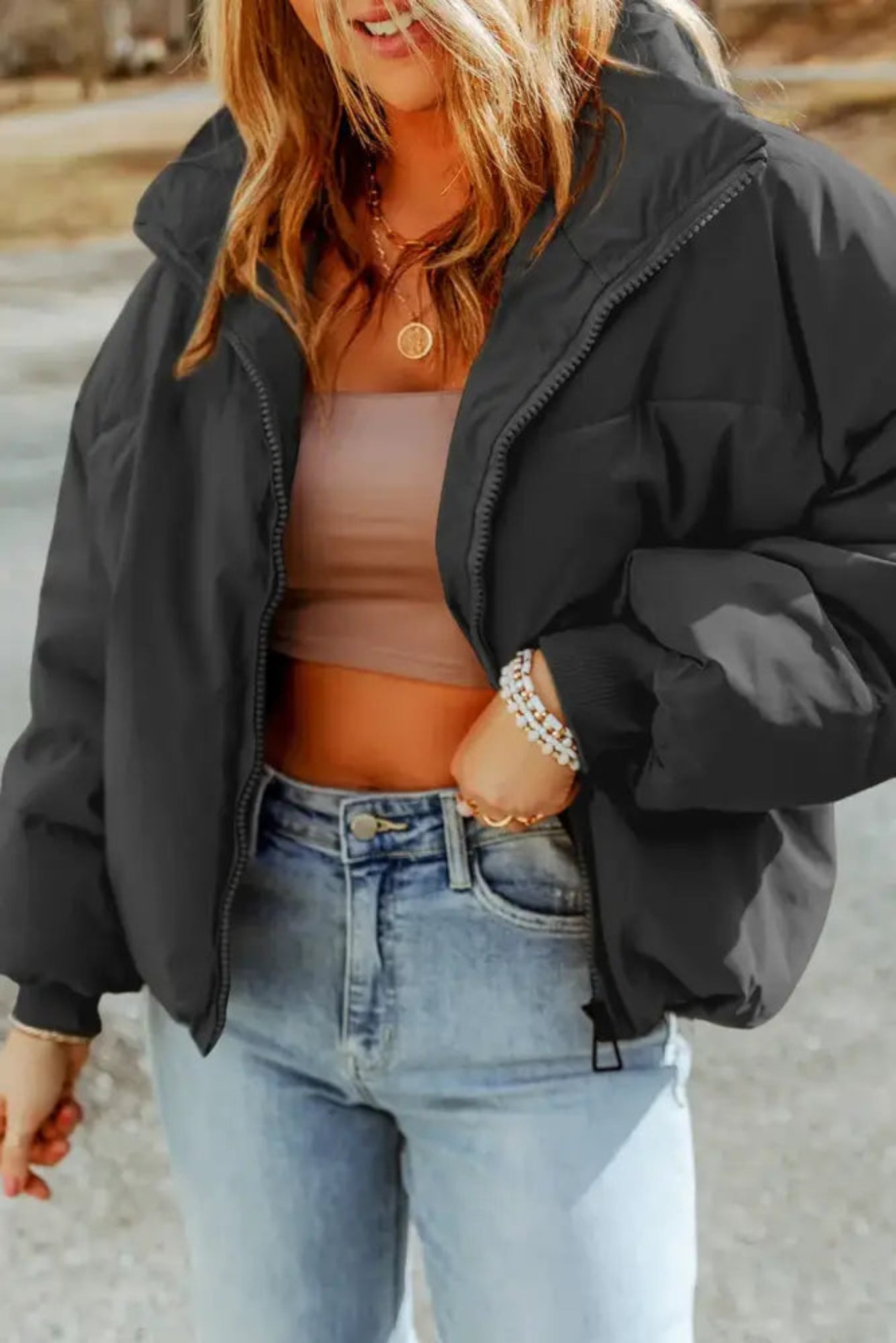 Person wearing a black puffer jacket and light blue jeans outdoors