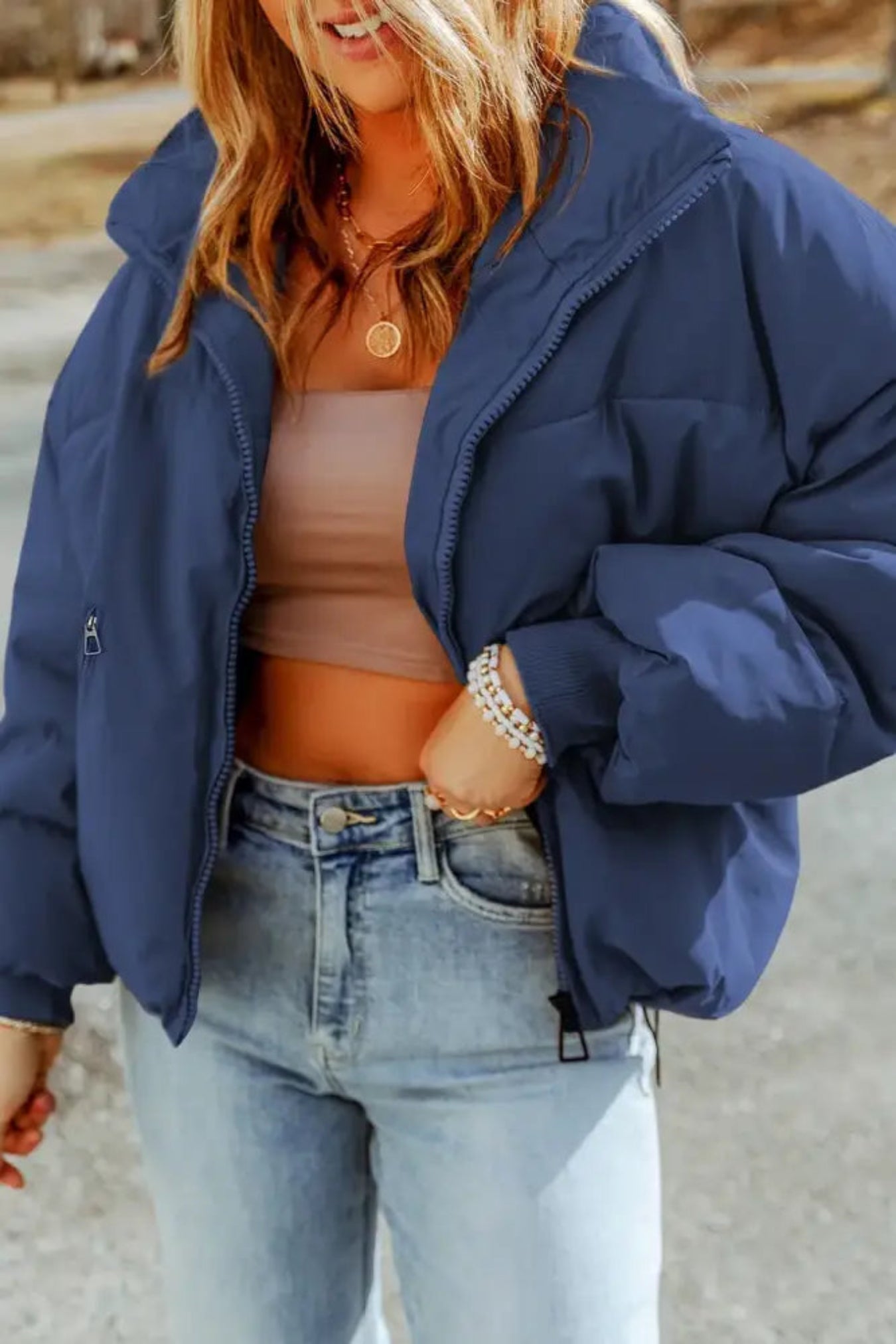 Person wearing a blue puffer jacket and light blue jeans outdoors