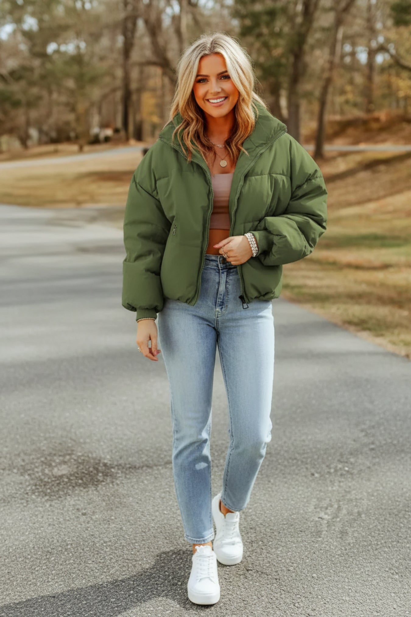 Person wearing a green puffer jacket and light blue jeans outdoors