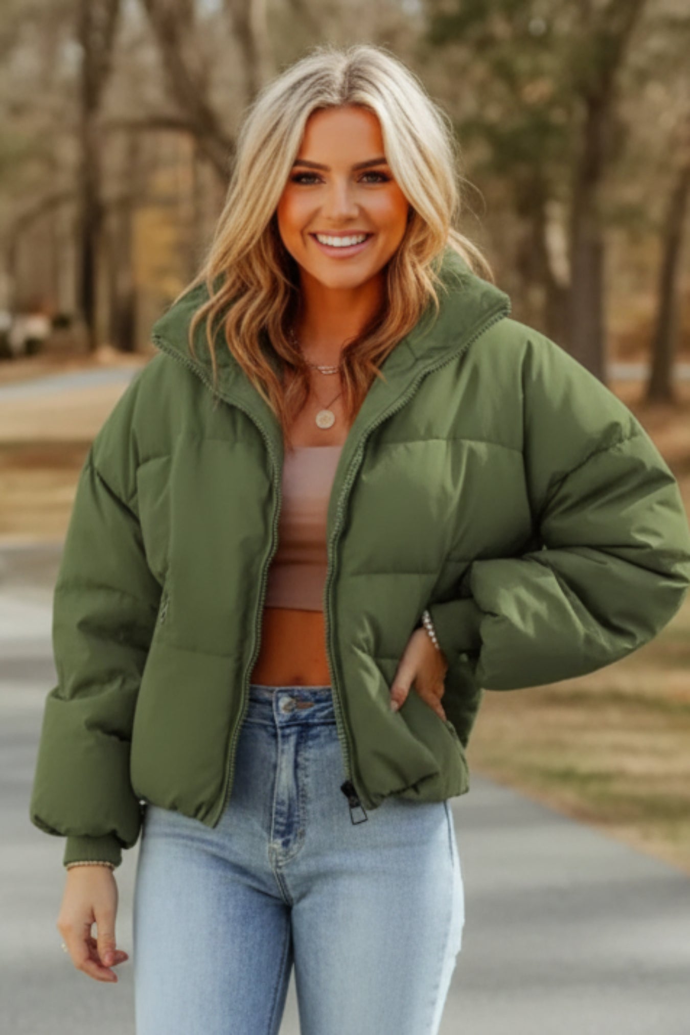 Person wearing a green puffer jacket and light blue jeans outdoors