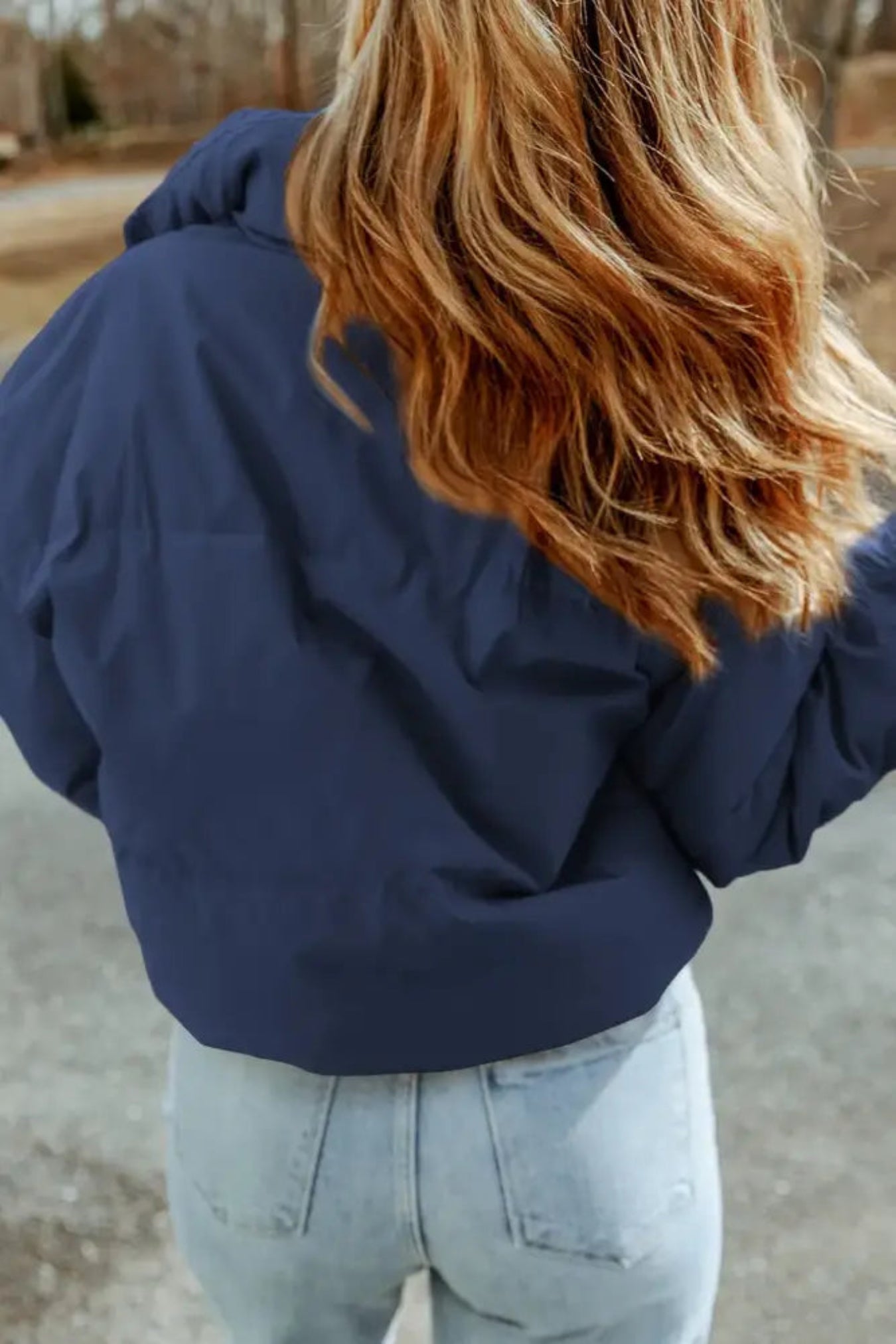 Person wearing a blue puffer jacket and light blue jeans outdoors