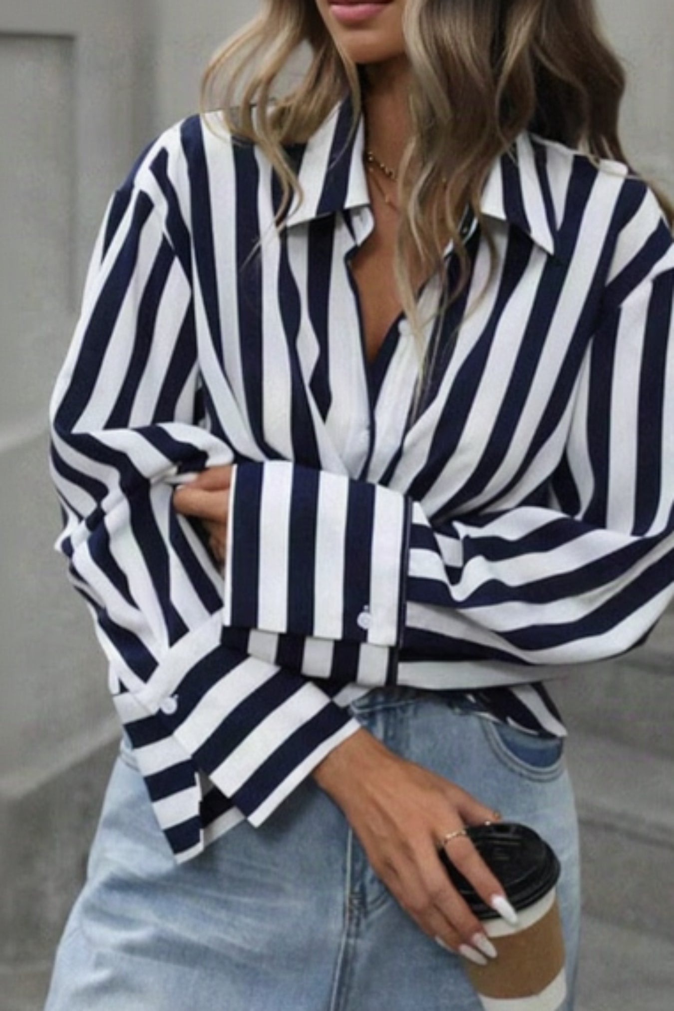 Woman wearing a navy and white striped shirt with light blue jeans, standing on steps.