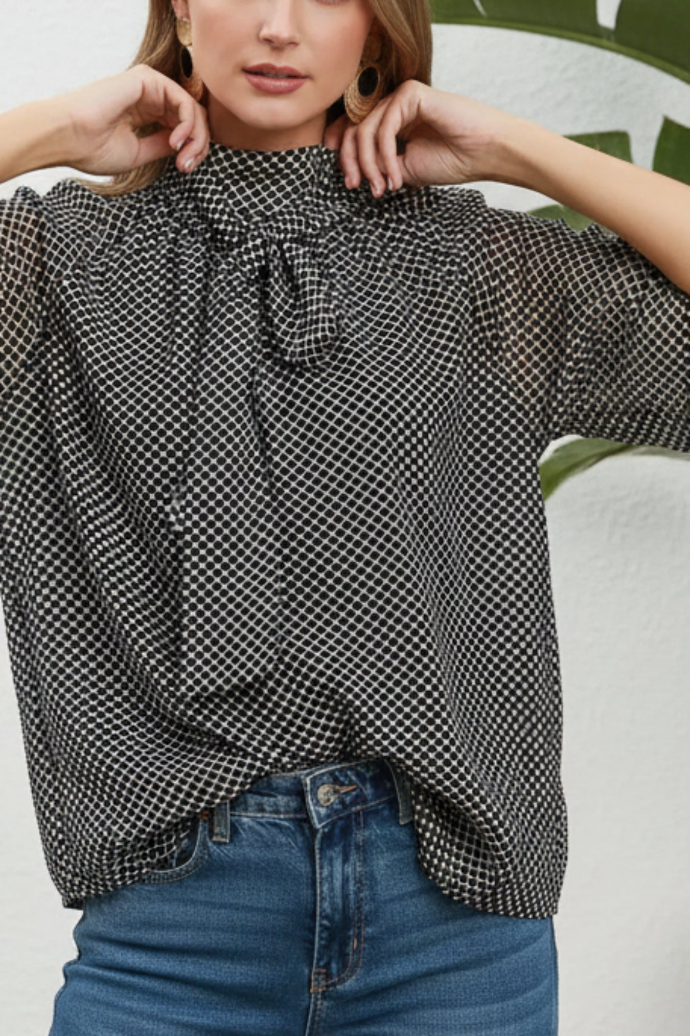 Woman wearing a black and white checkered blouse with a white background